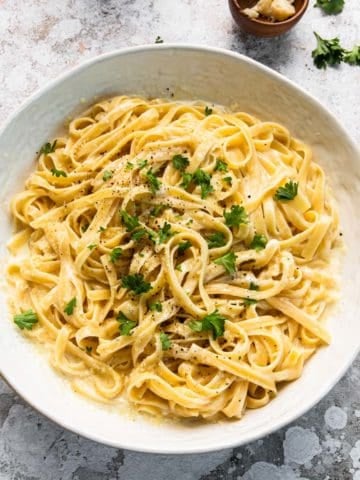 white serving bowls of fettuccine alfredo