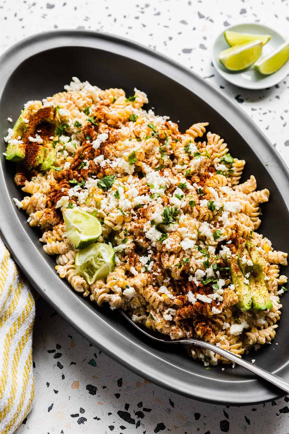 a large black platter filled with mexican street corn pasta salad