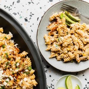 top down view of a plate of mexican street corn pasta salad with a partial view of large platter on right