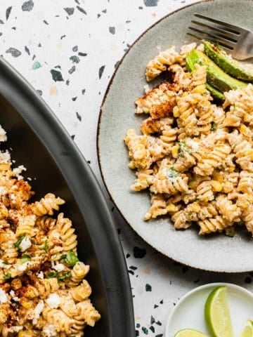 top down view of a plate of mexican street corn pasta salad with a partial view of large platter on right