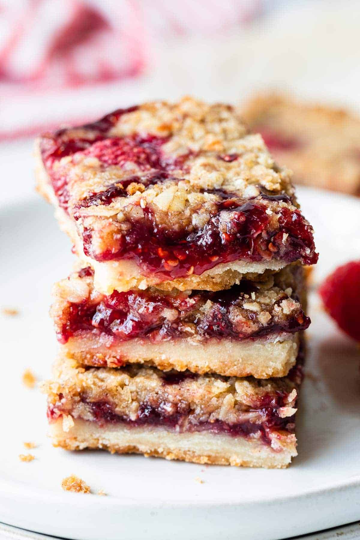 raspberry bars stacked on a white palate