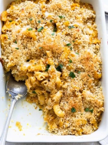 pumpkin mac and cheese in a casserole dish with a portion missing