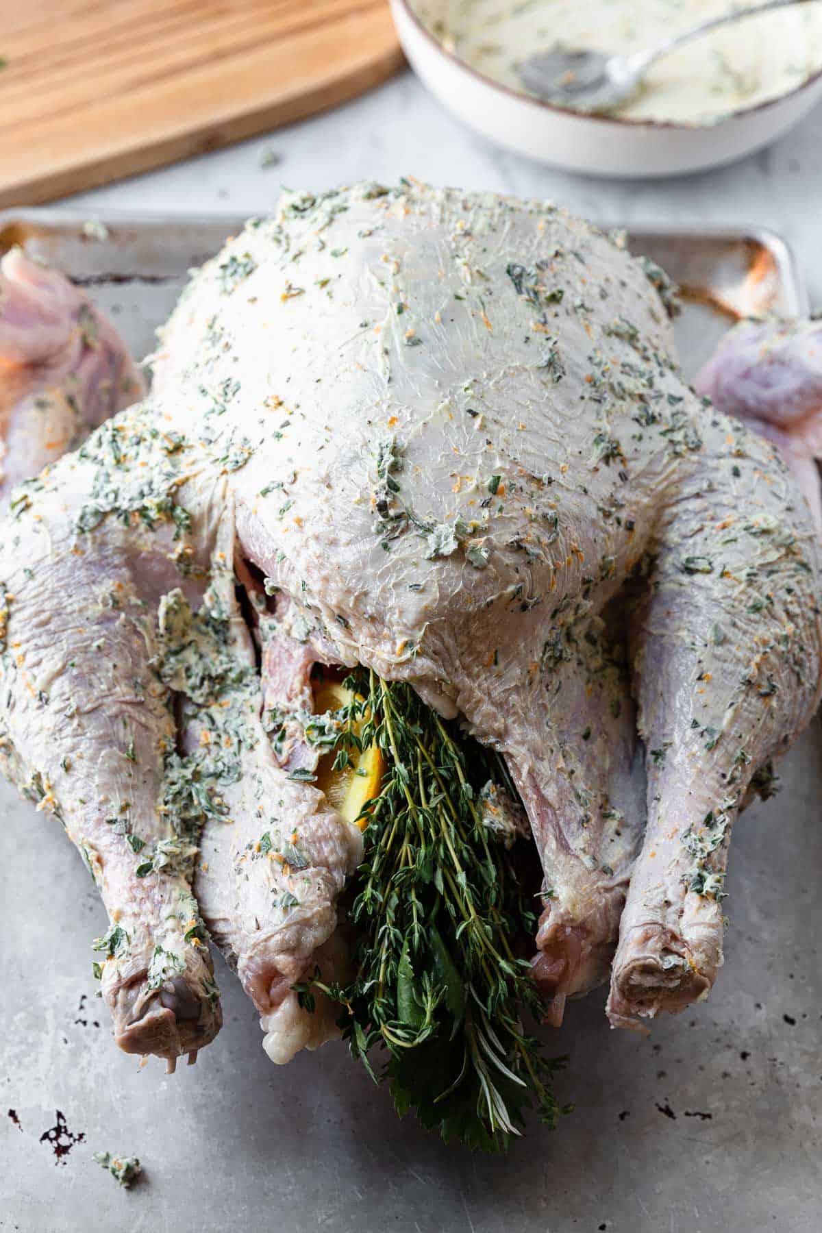 raw whole turkey covered in orange herb butter