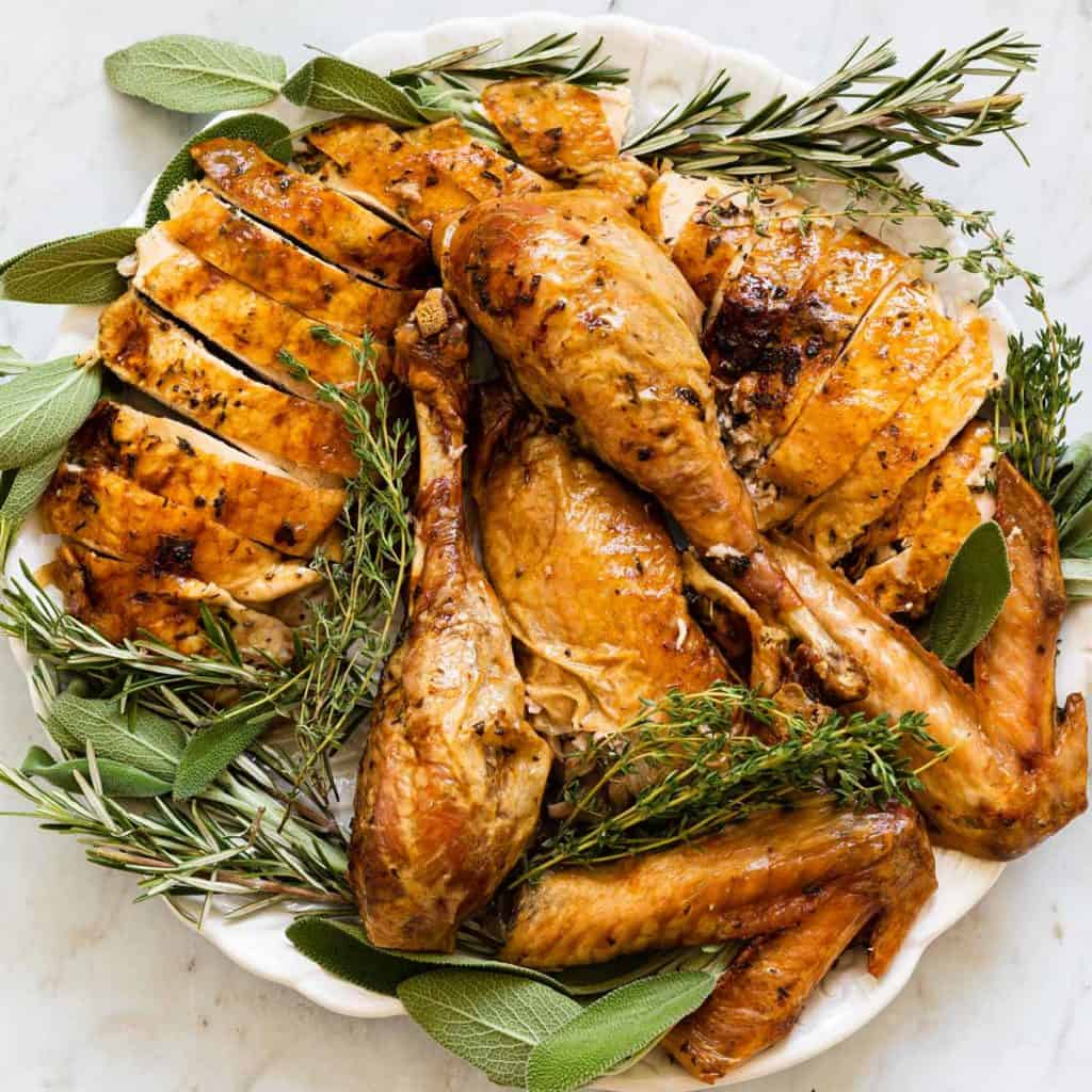 roasted turkey cut up on a platter with fresh herbs