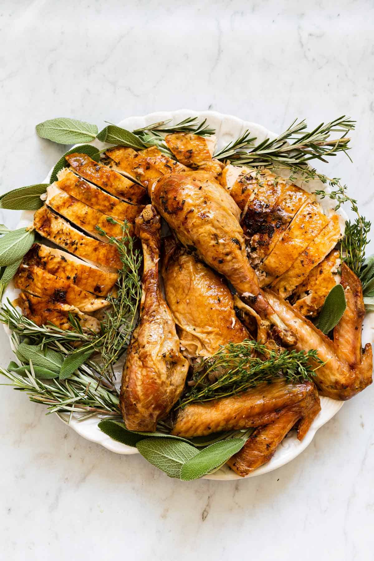 round platter with cut up roasted turkey and fresh herbs