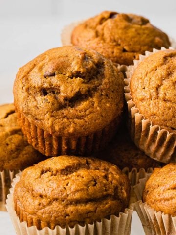 Pumpkin chocolate chip muffins stacked on a plate.