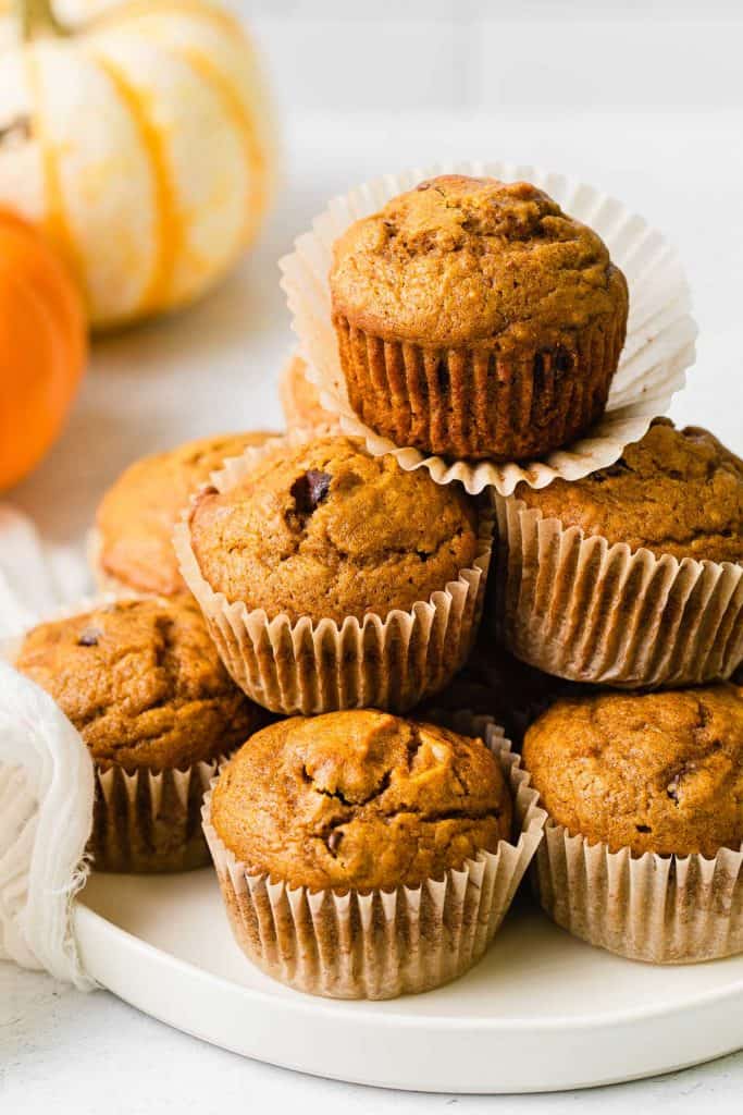 Pumpkin chocolate chip muffins stacked on a plate.