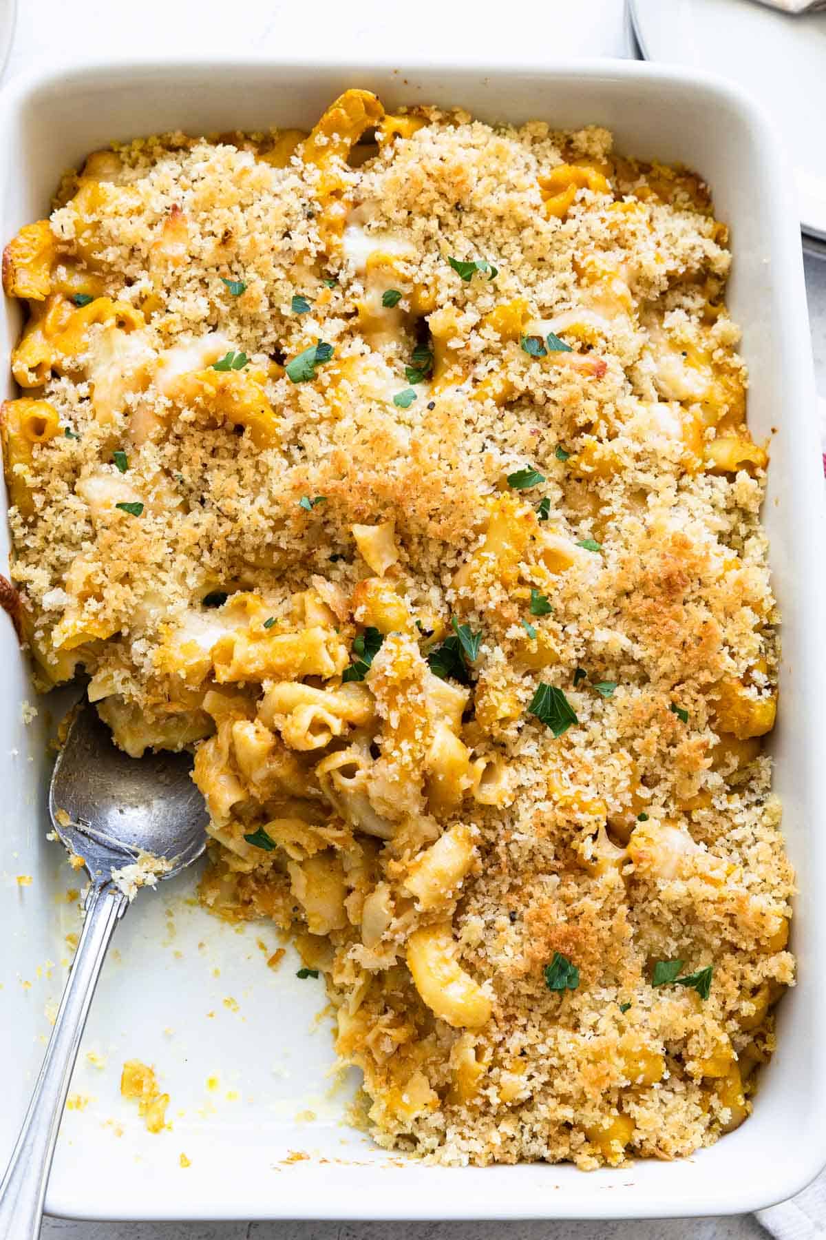 pumpkin mac and cheese in a casserole dish with a portion missing