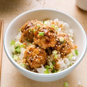 close view of chicken meatballs with teriyaki sauce, rice and sesame seeds