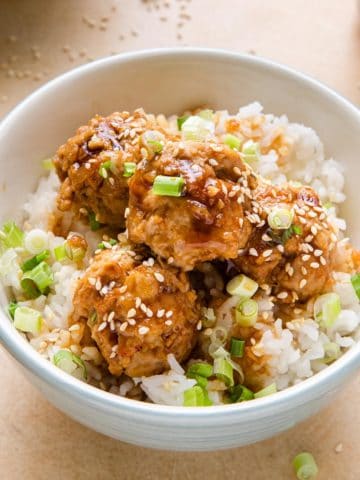 close view of chicken meatballs with teriyaki sauce, rice and sesame seeds