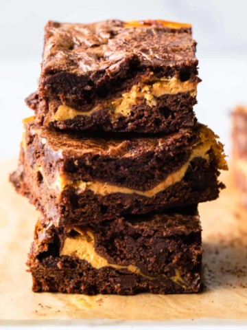 Stack of pumpkin brownies on parchment paper.