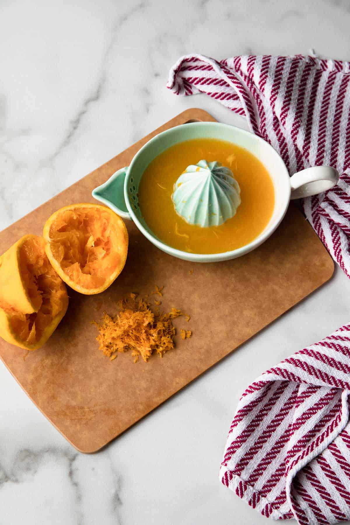 Zested and juiced orange on a cutting board.