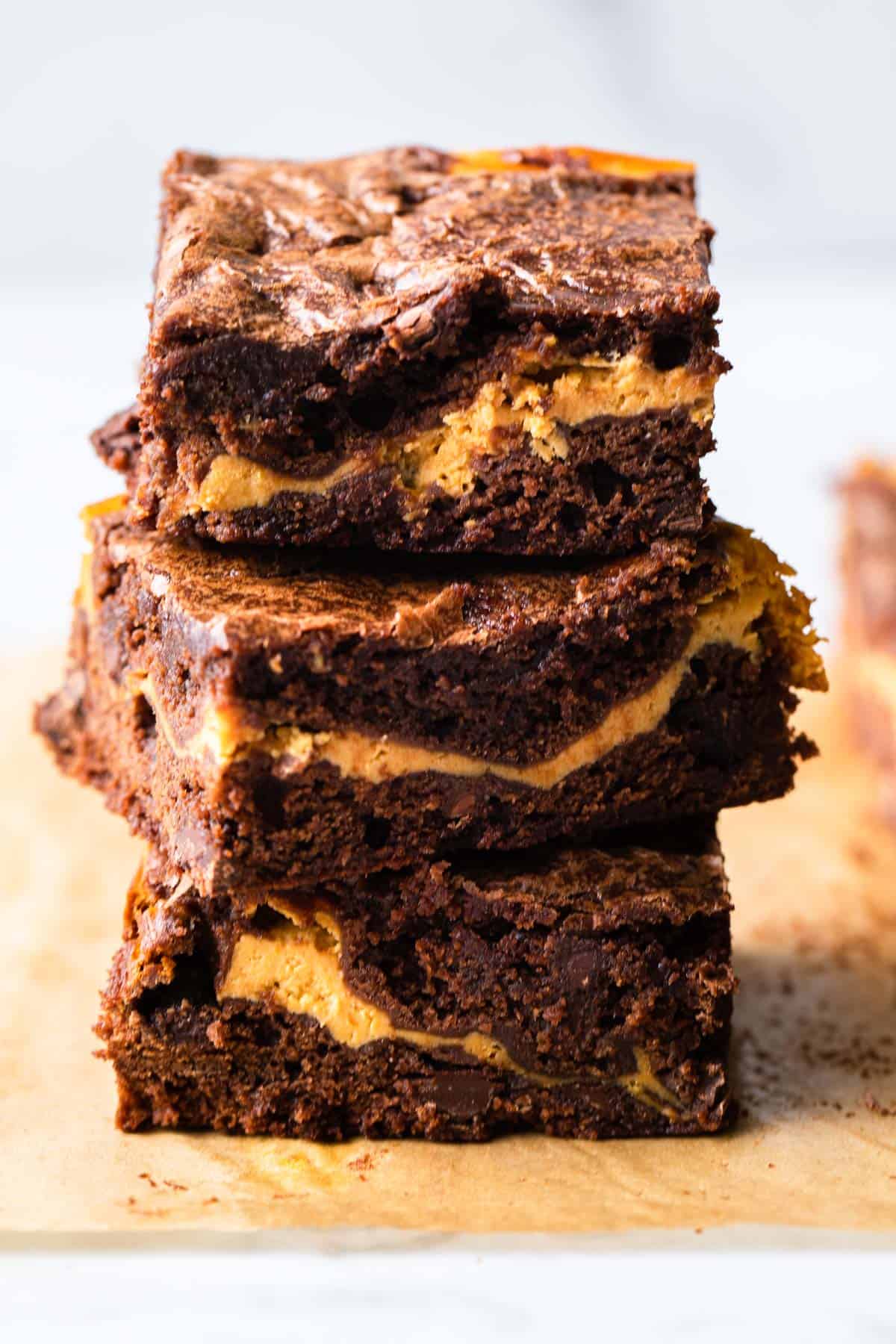 Stack of pumpkin brownies on parchment paper.