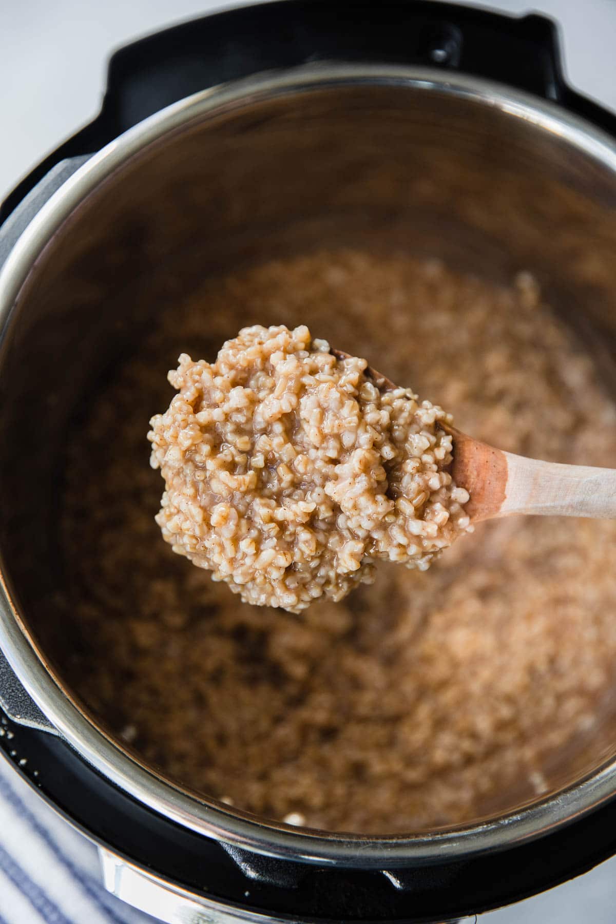 A wooden spoon with a scoop of cooked steel cut oatmeal.
