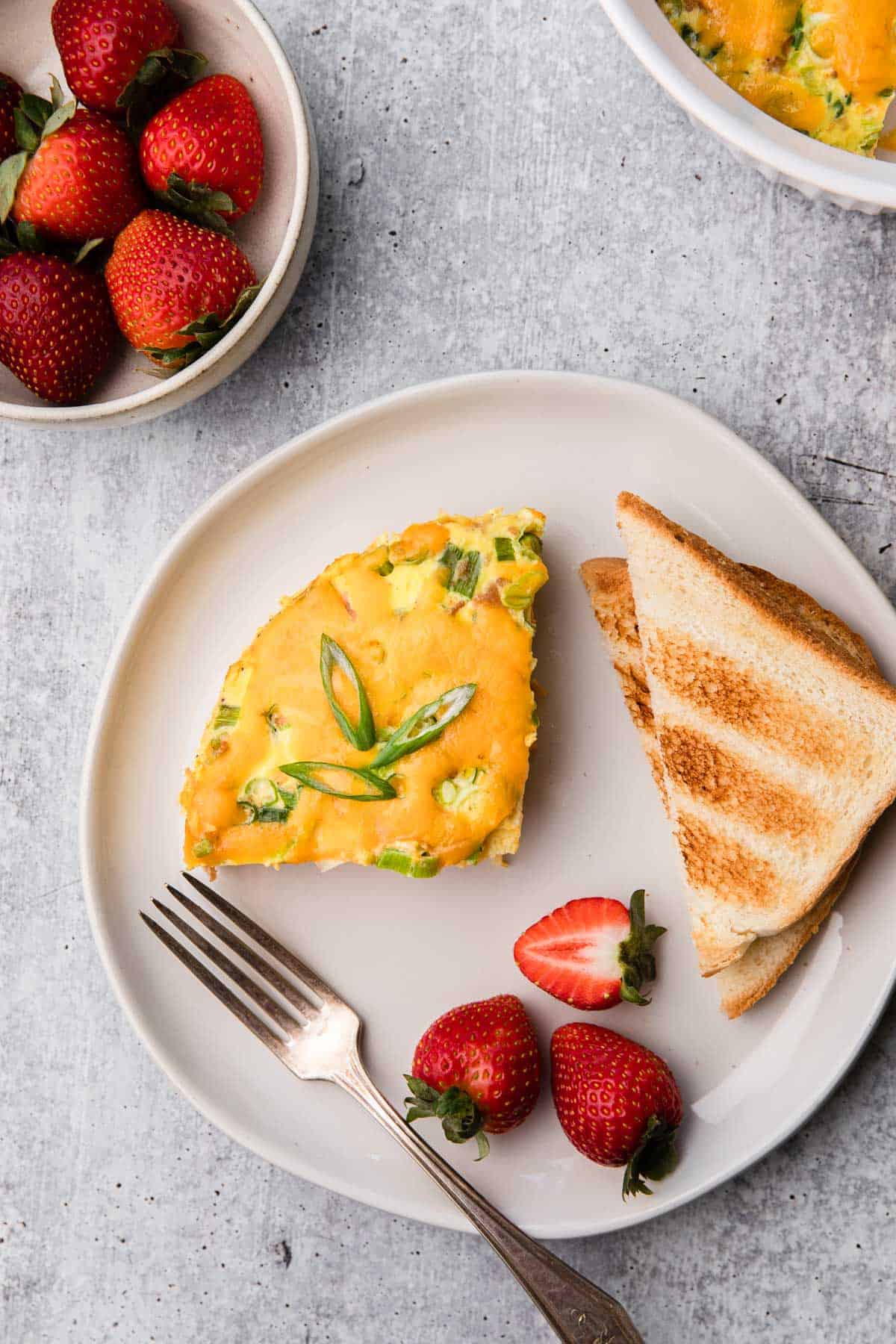Plate with breakfast casserole, toast and strawberries.