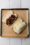 Adding meat and cheese to hoagie rolls.