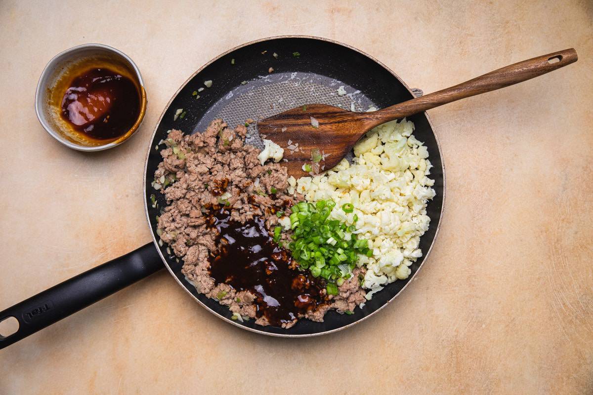 adding cauliflower to cooked meat