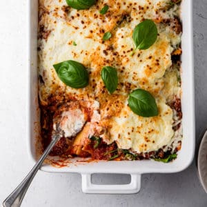 casserole dish with baked ravioli and basil leaves