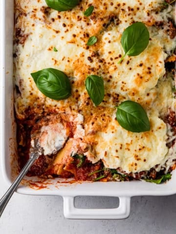 casserole dish with baked ravioli and basil leaves