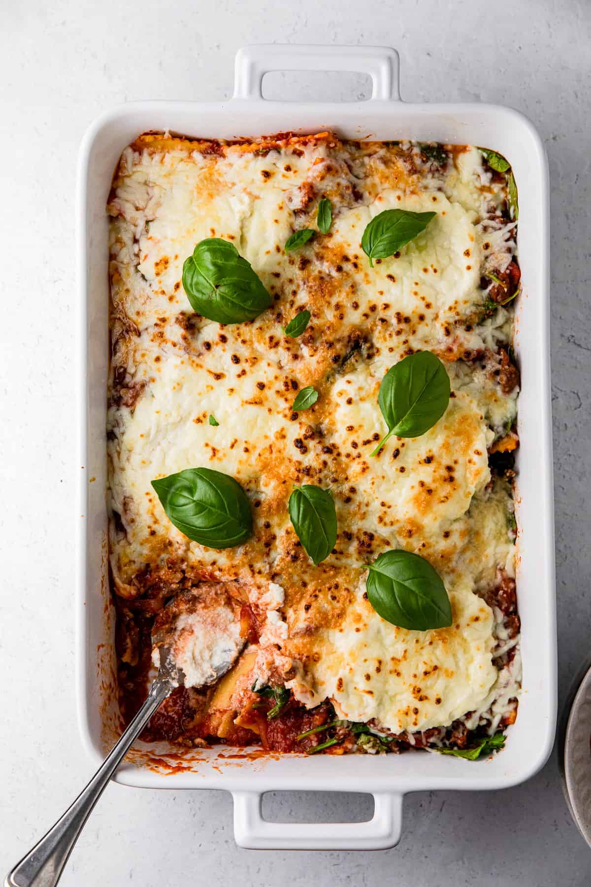 spinach ricotta ravioli dish with baked ravioli and basil leaves