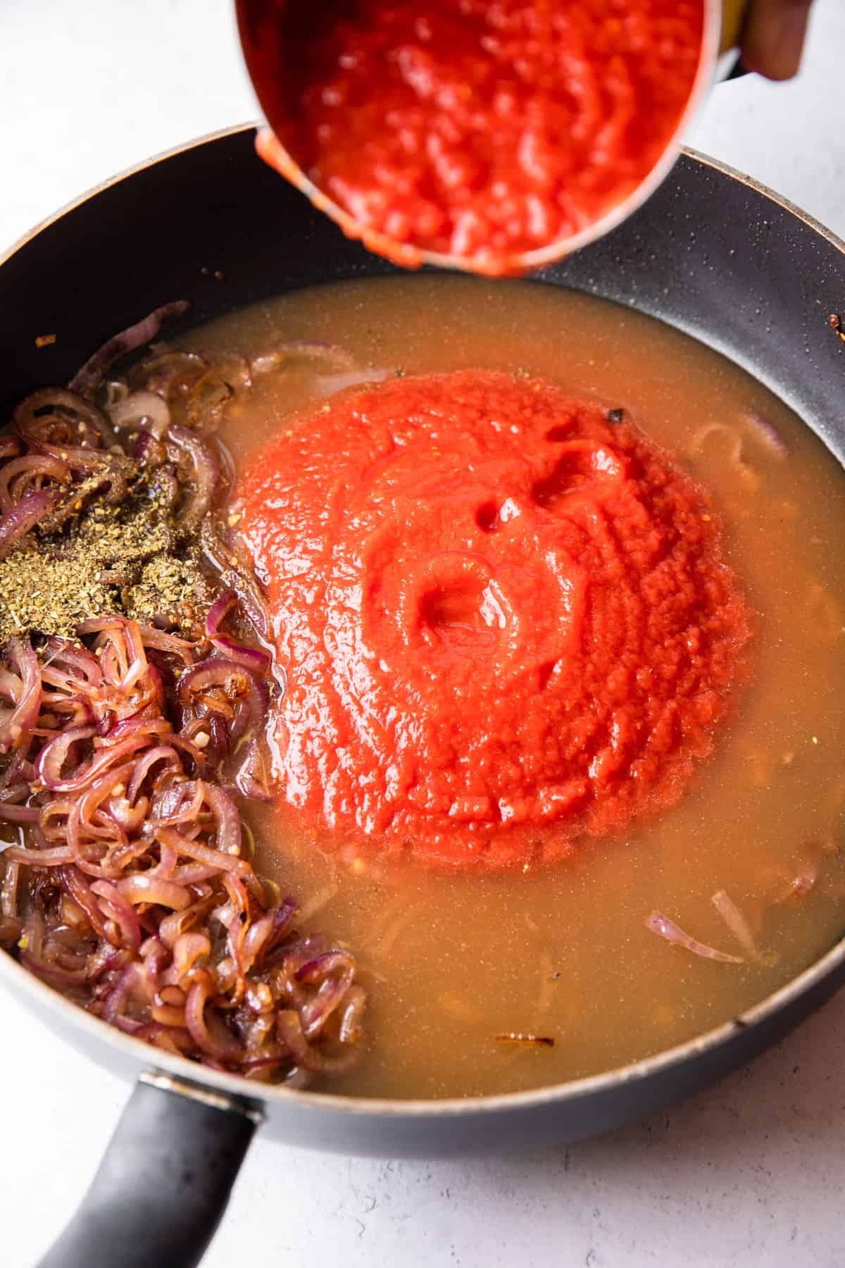 cooking ground beef, onions, and adding tomato sauce to pan