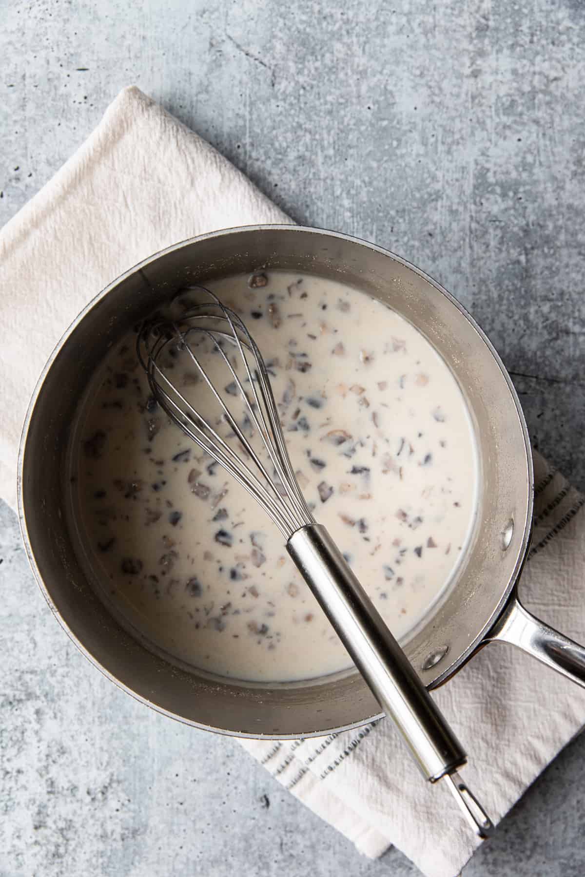 chopped mushrooms and chicken broth in a saucepan, whisking milk into the saucepan