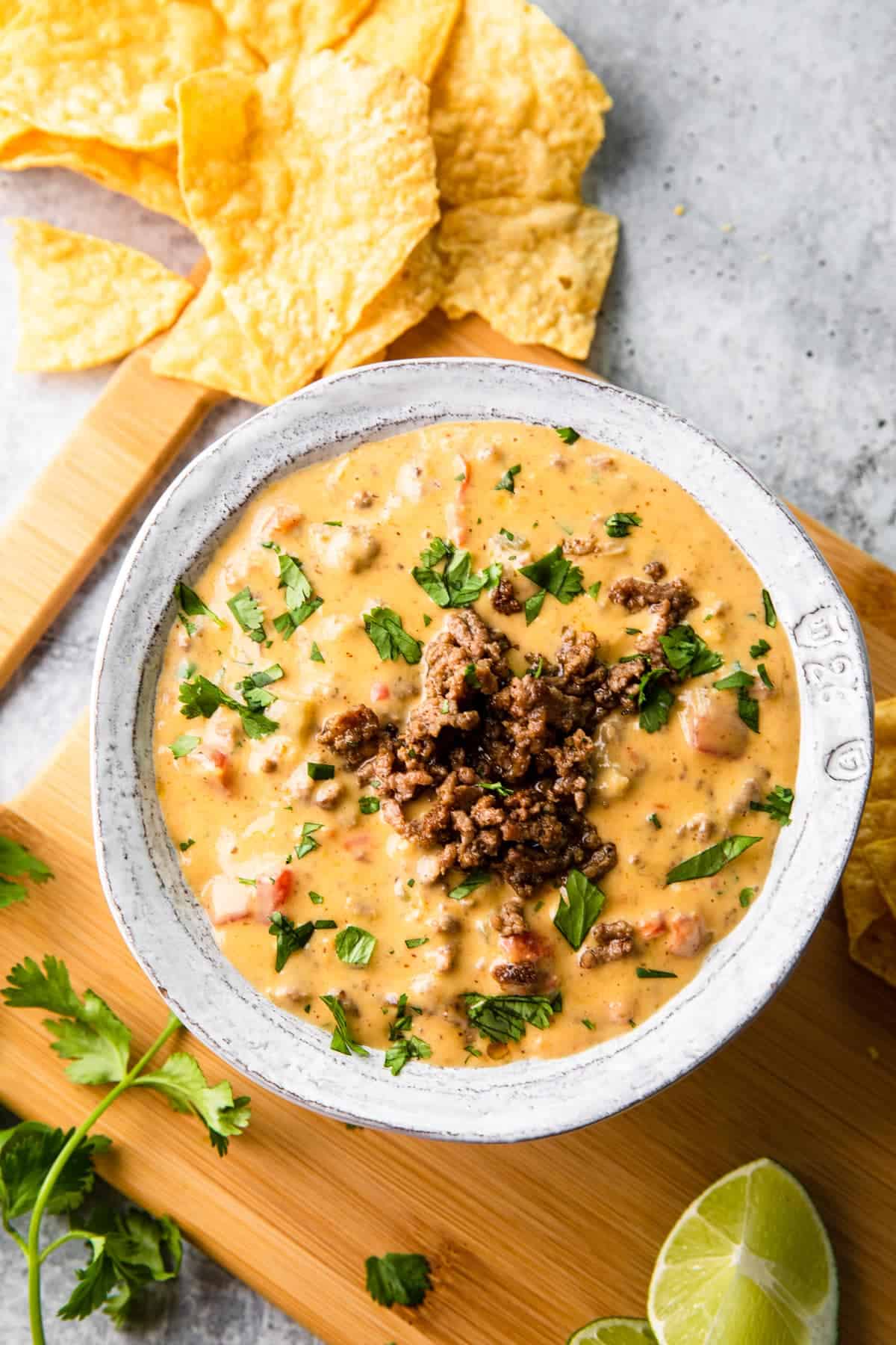 a bowl of meat and cheese dip with some tortilla chips on the side