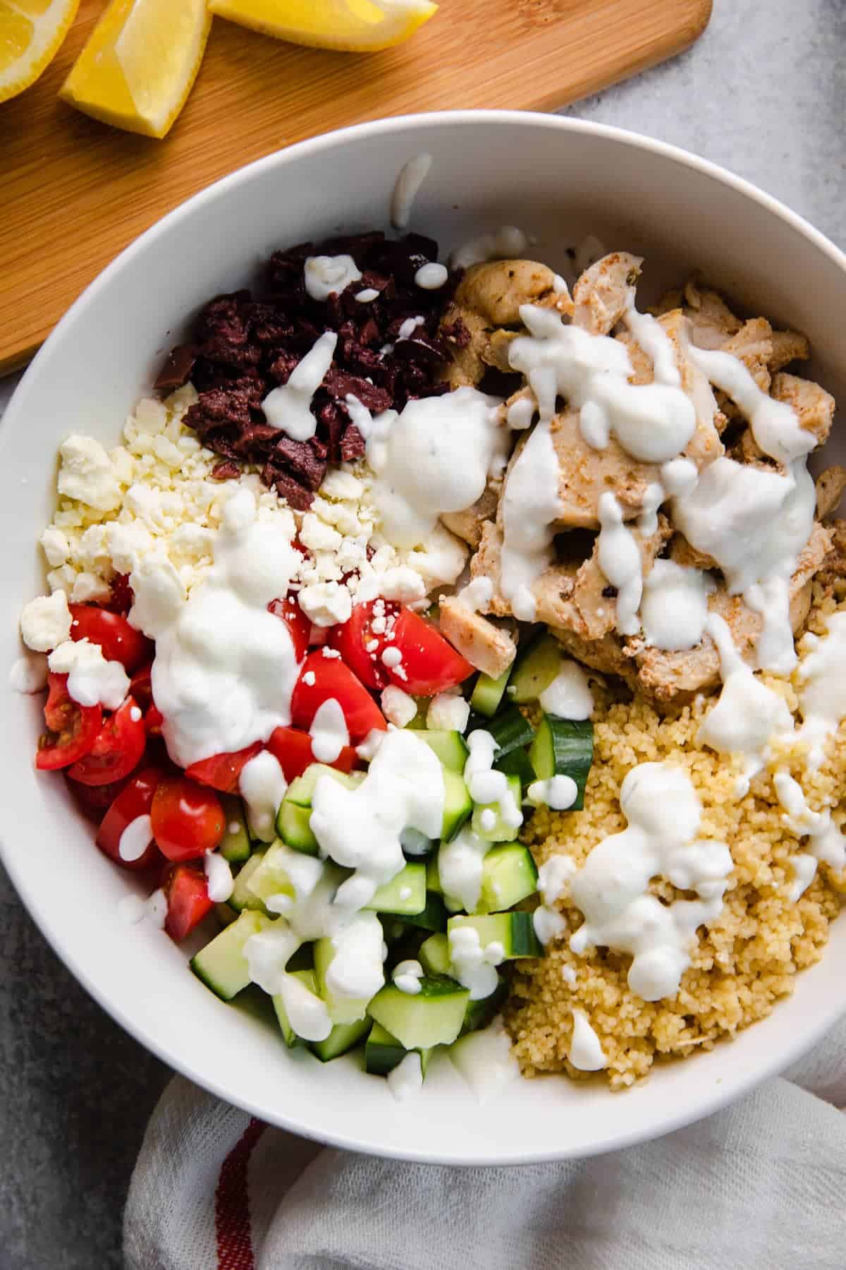 greek chicken bowl with yogurt sauce drizzled on it