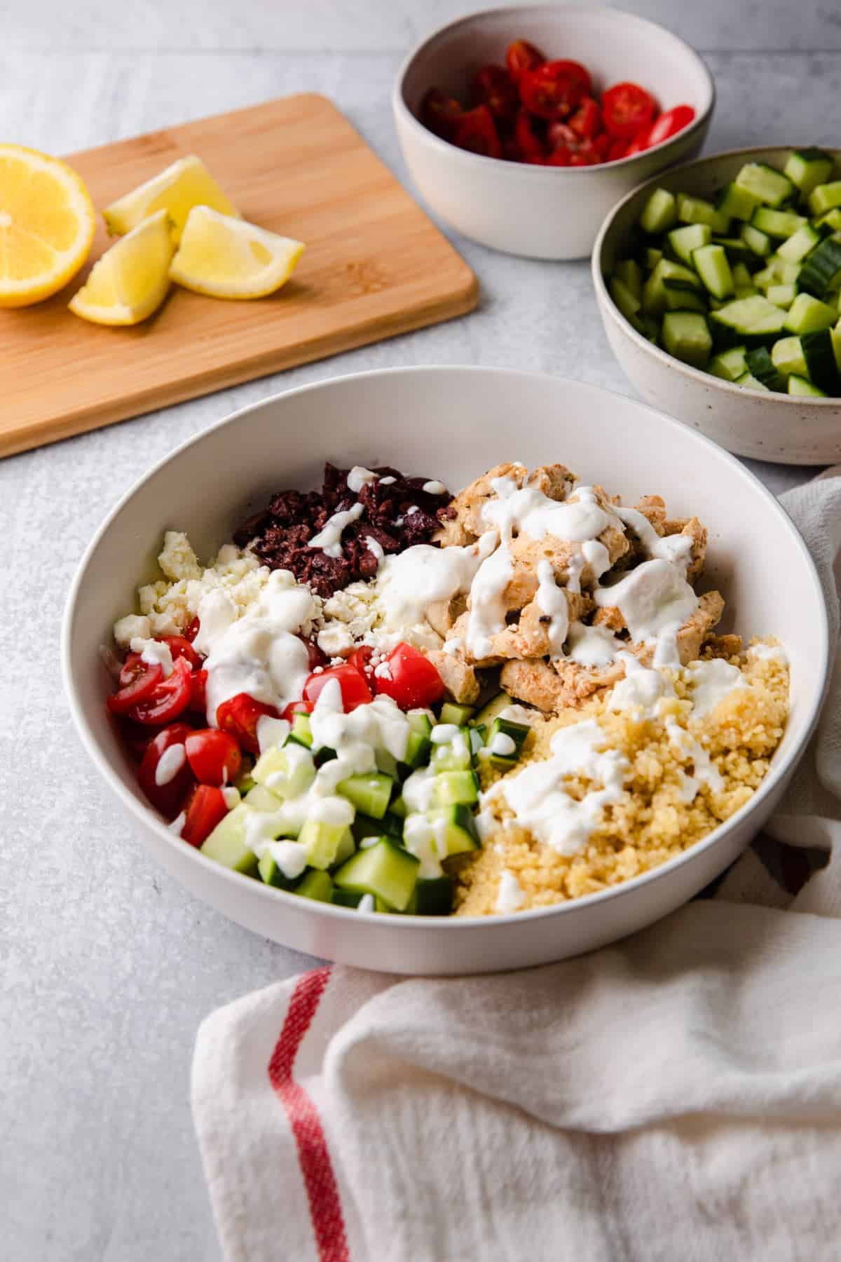 greek chicken bowl with extra ingredients in the background