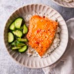 sweet chili salmon recipe prepared in a bowl over rice and cucumbers