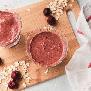chocolate cherry smoothie on a wooden board with a few rolled oats on the side