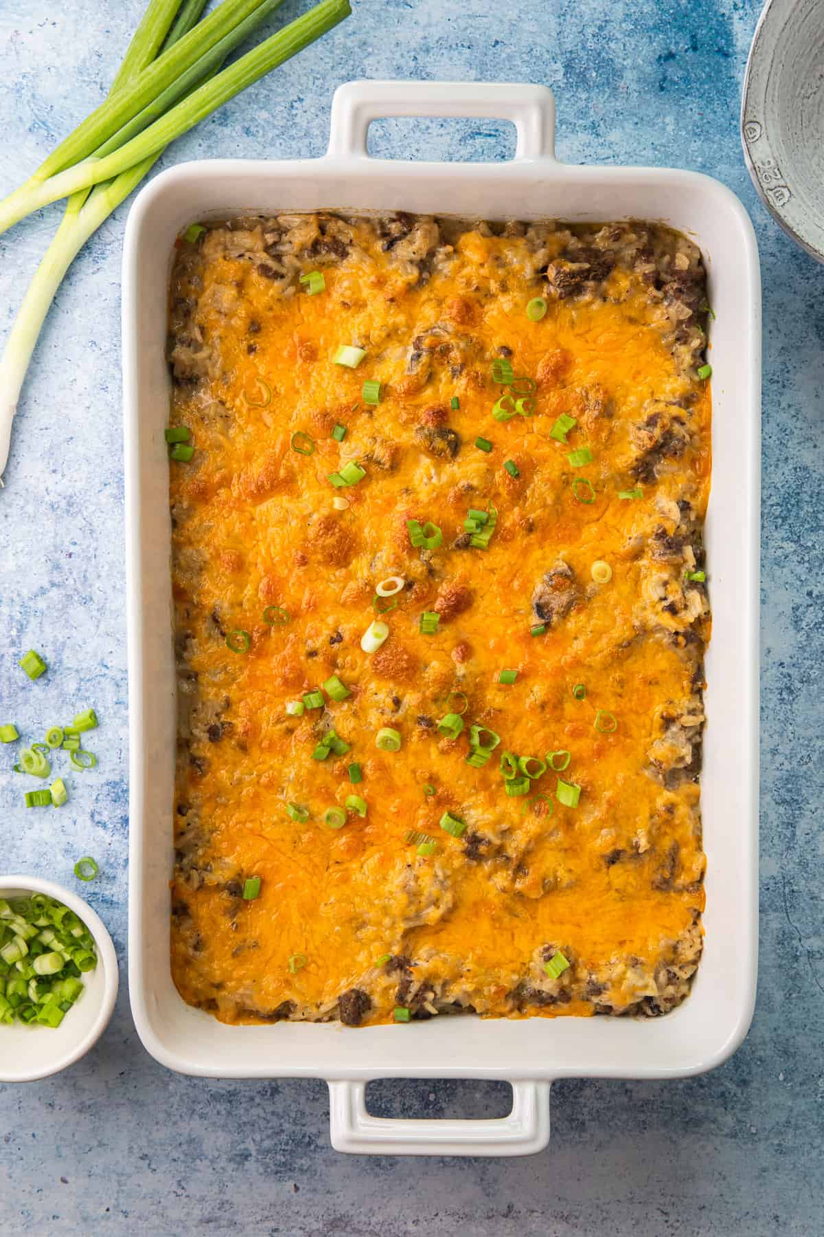 a casserole dish with baked rice and ground beef mixture topped with melted cheese