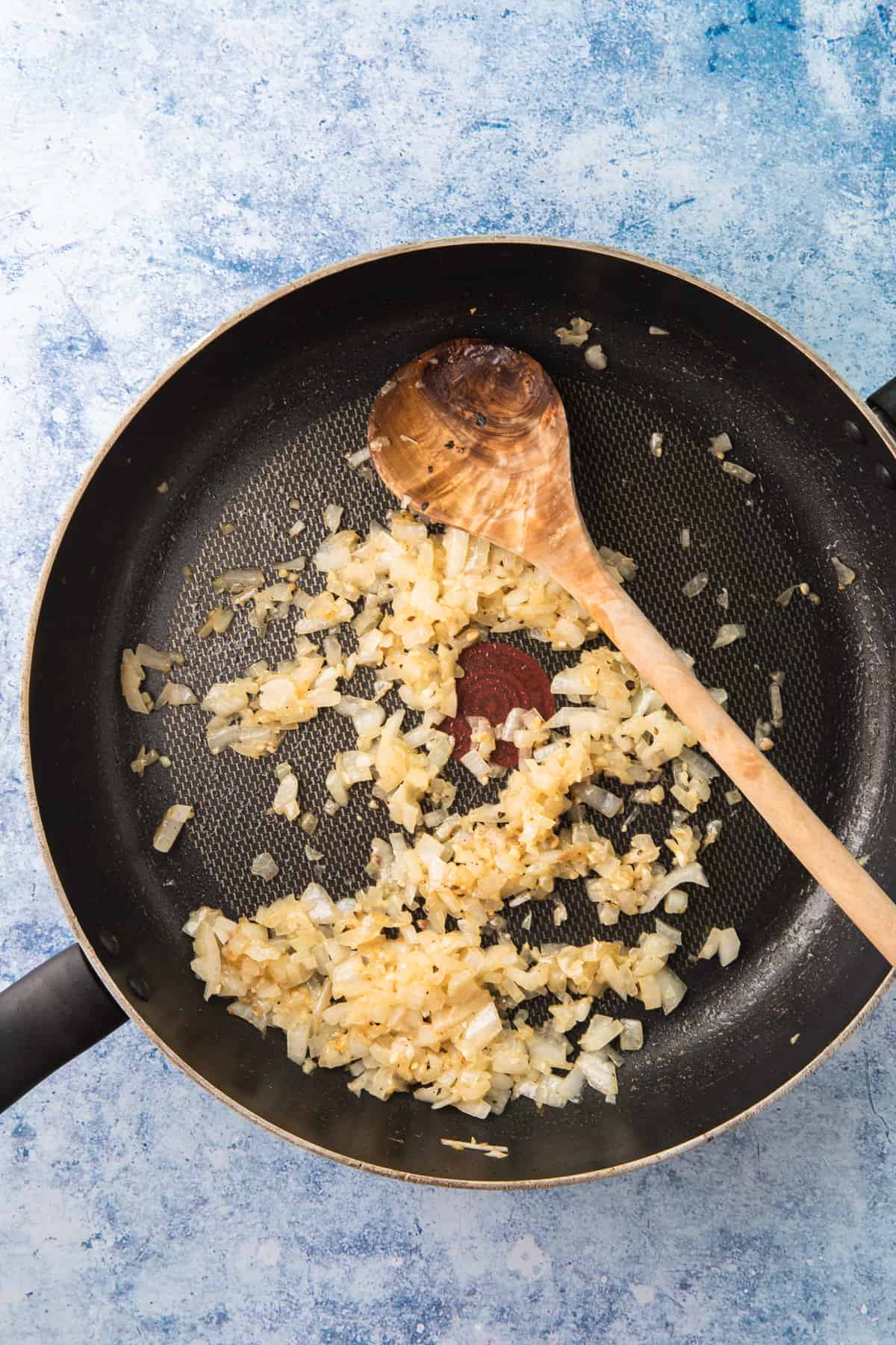 raw ground beef in a skillet, sauted onions in a skillet