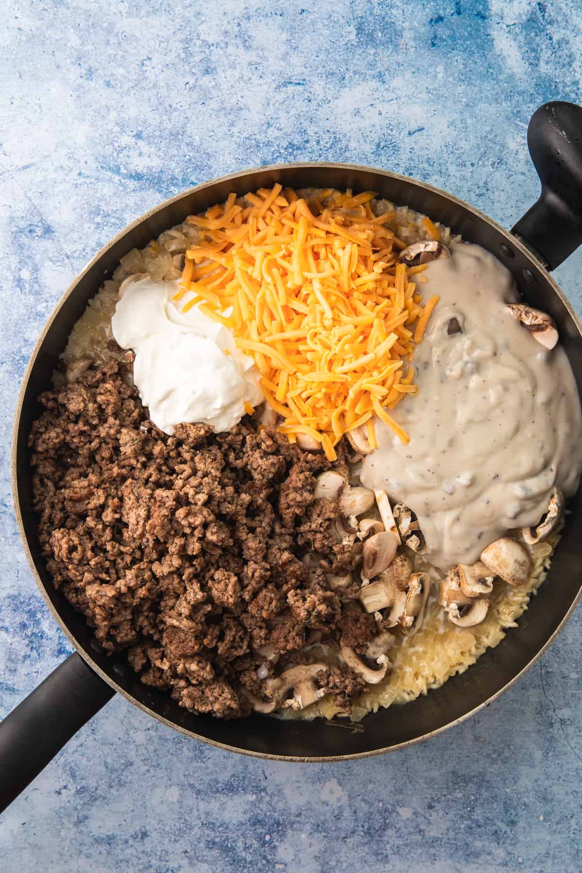 making recipe in a skillet, adding rice, mushrooms, broth, and ground beef