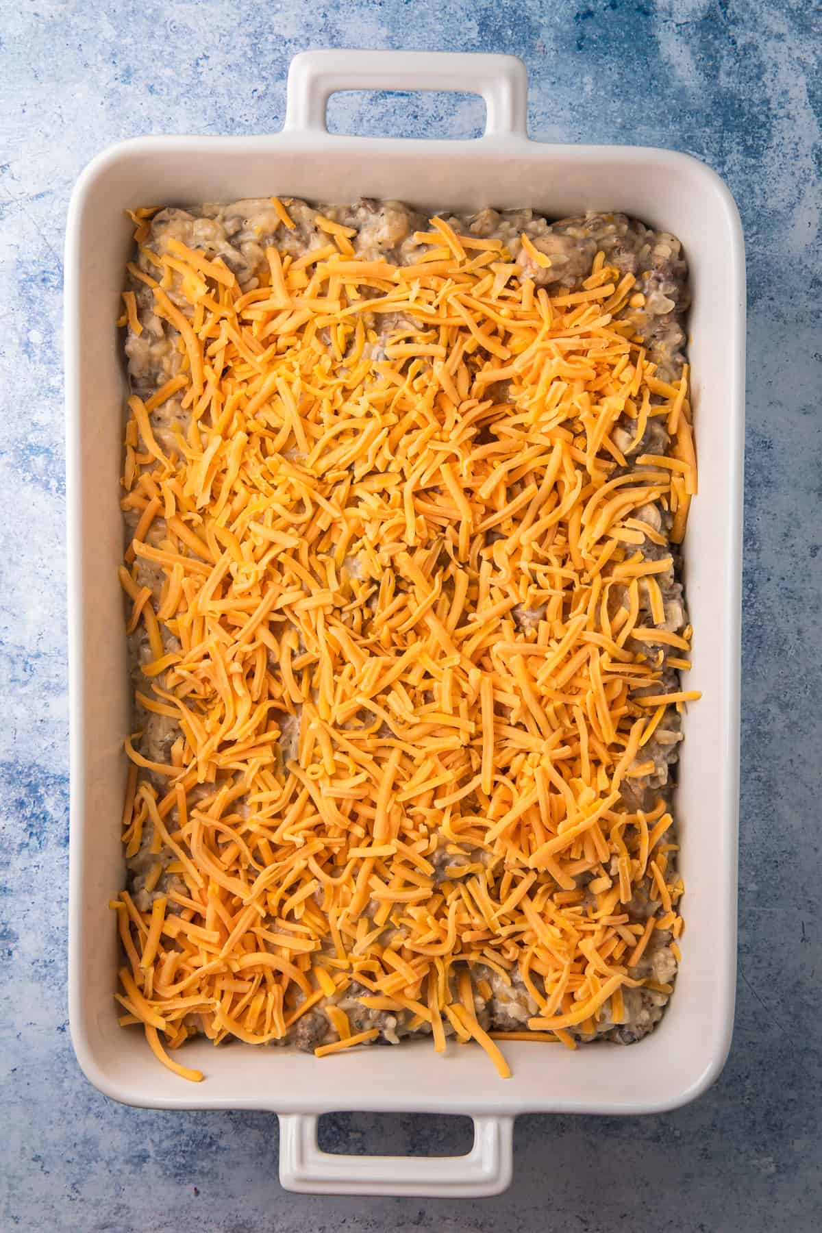 a casserole dish filled with a ground beef and rice mixture and cheese topping