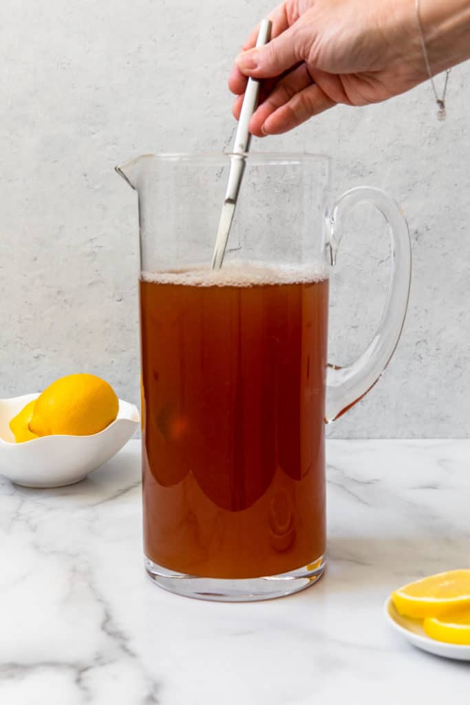 mixing brewed tea and lemonade in a glass pitcher