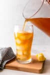 pouring iced tea lemonade mixture into a glass filled with ice