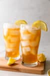 two glasses of iced tea lemonade with lemon wedges