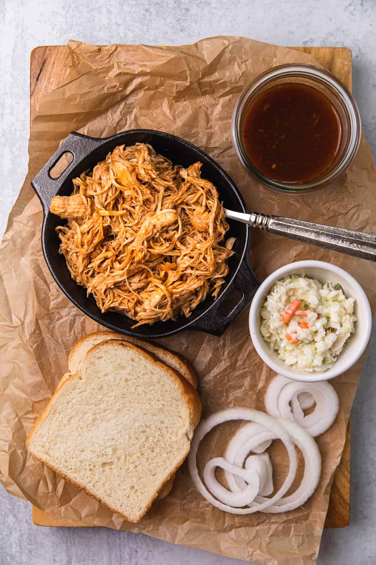 shredded bbq chicken in pan with fixins on the side