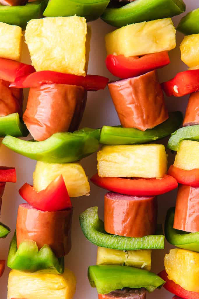 green and red peppers with pineapple and sausage on a skewer.