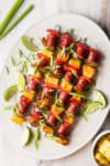 a platter of kabobs with green onions scattered