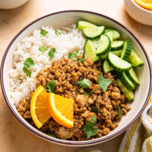 a bowl of ground orange chicken with orange slices