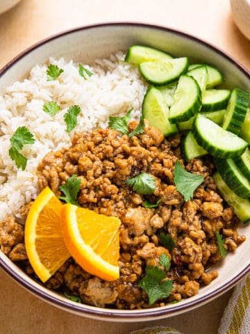 a bowl of ground orange chicken with orange slices