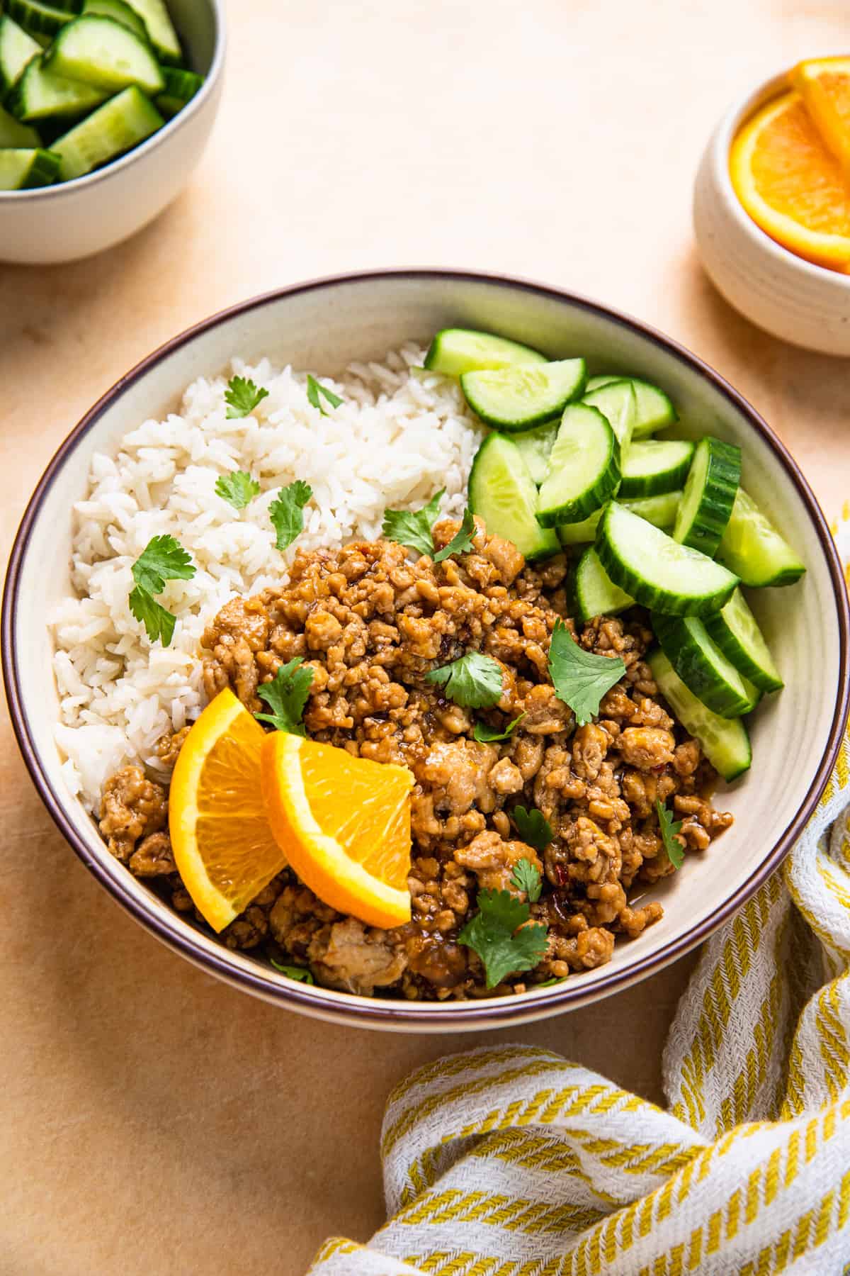 orange chicken with rice, cucumbers, and orange slices