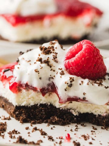 Chocolate Raspberry Dessert Bars on a white plate and topped with a fresh rapsberry.