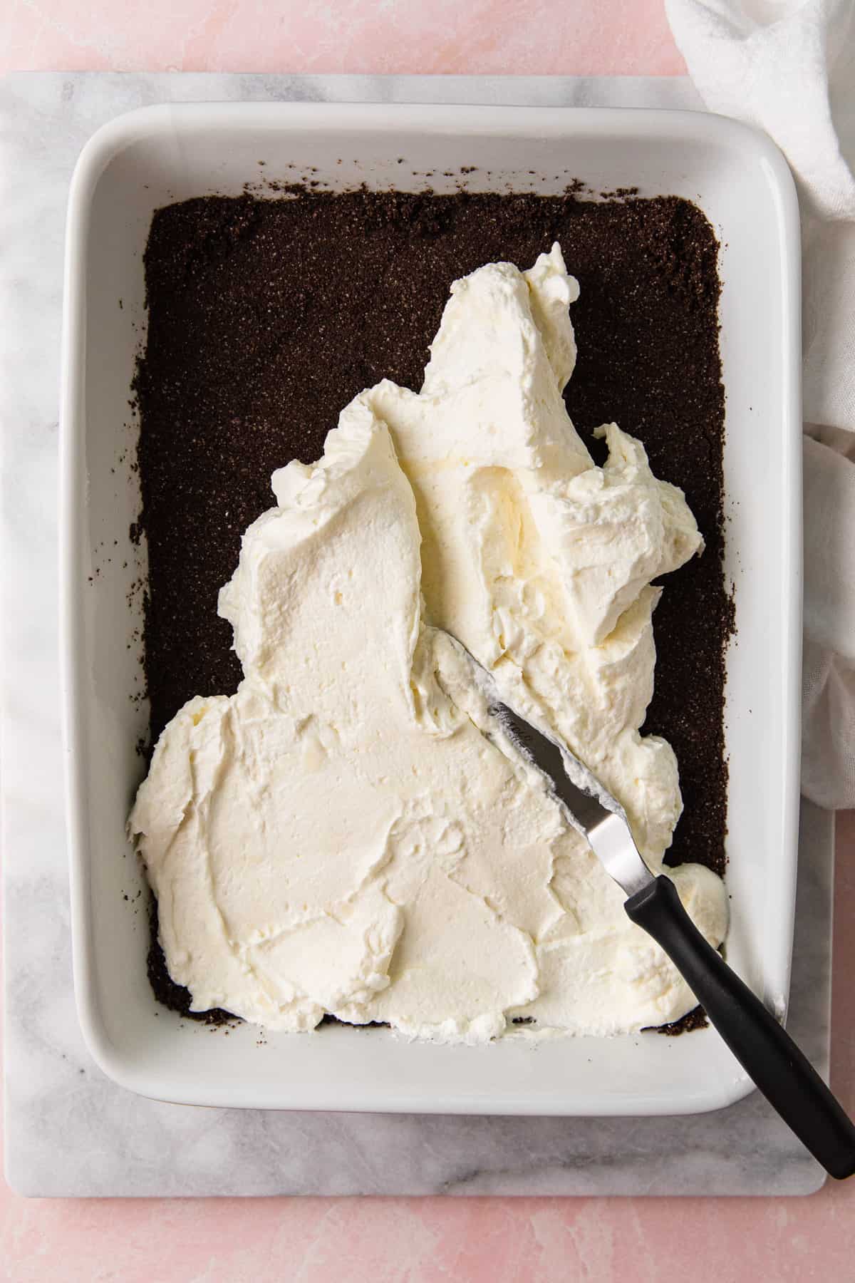 Spreading cream cheese mixture over chocolate crust.