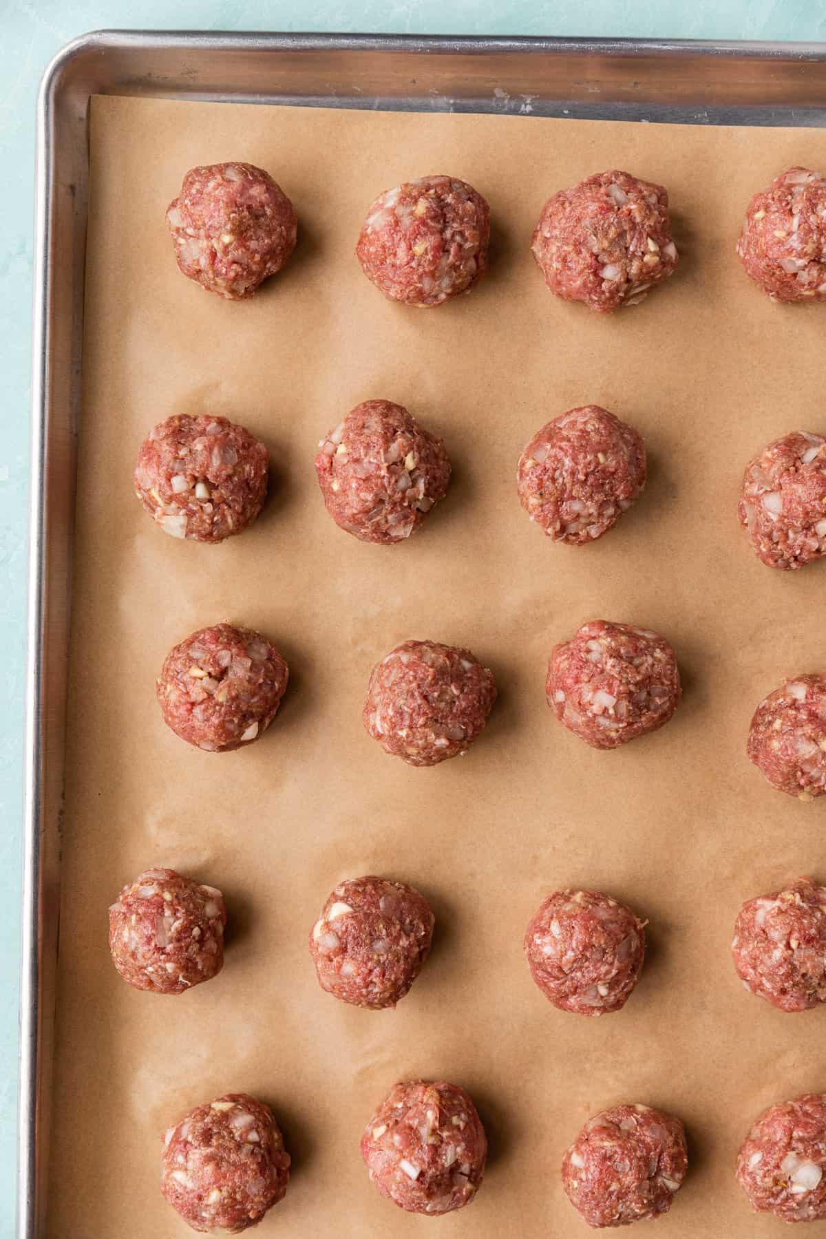 Meatballs formed in a baking sheet.