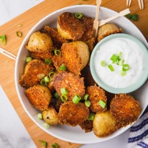 parmesan crusted potatoes in a bowl with a creamy white dip and green onions