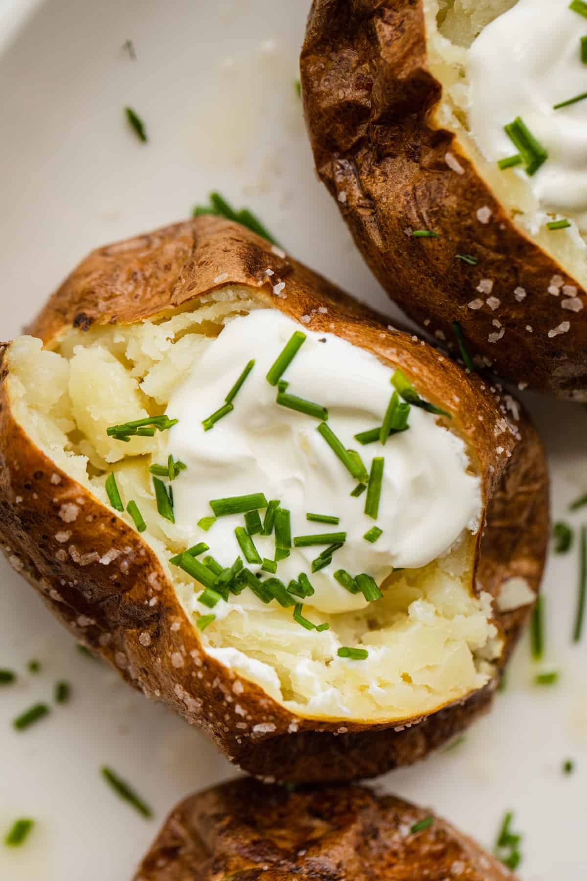 a baked potato split open with sour cram and chives