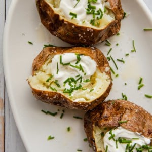 baked potatoes with sour cream and chives on a white platter